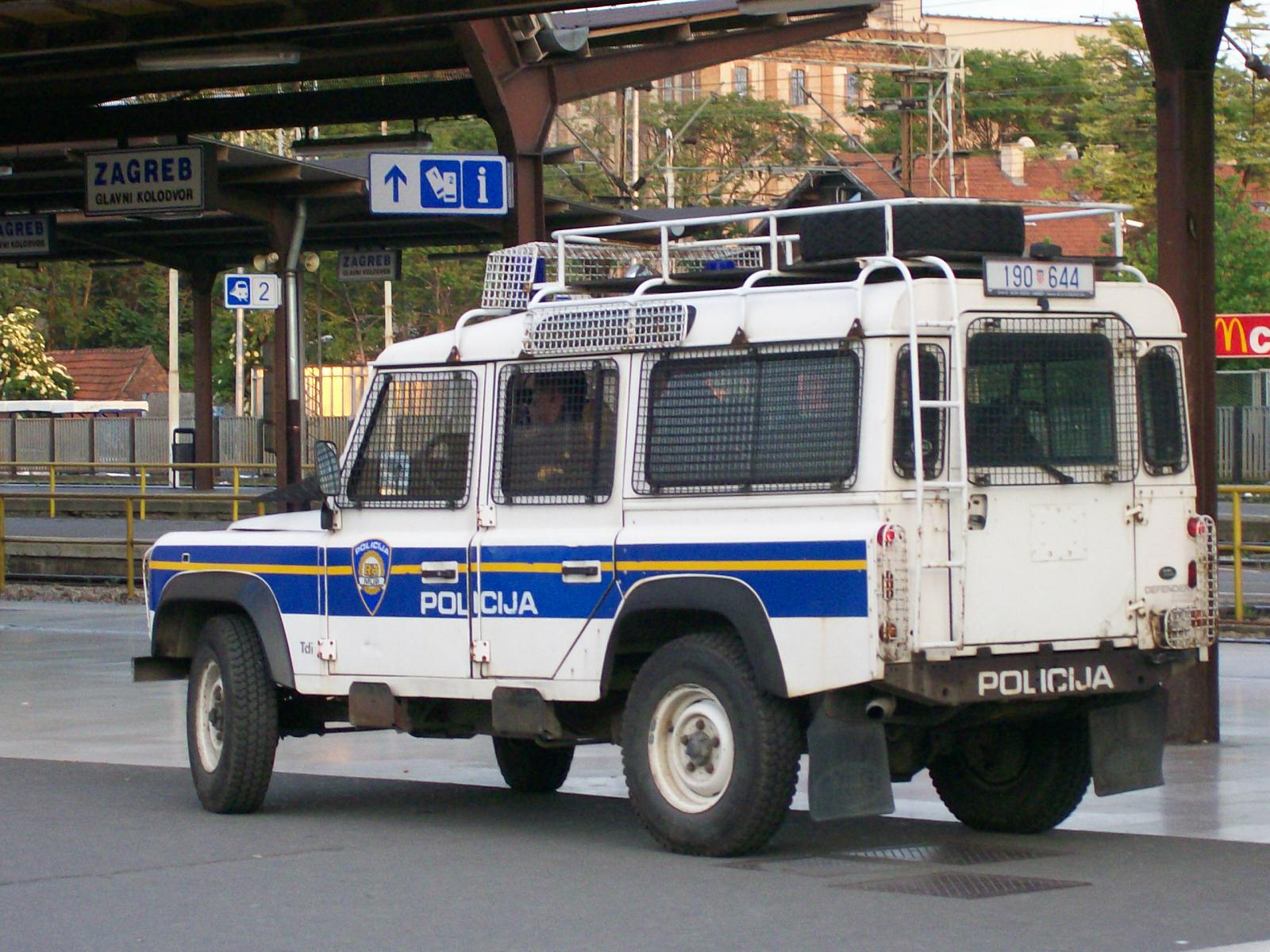Croatian police Defender 110 Station Wagon 190 644 outside Zagreb Glavni kolodvor, 2008 — mesh guards over all glazing, roof rack with spare and identification board, rear access ladder