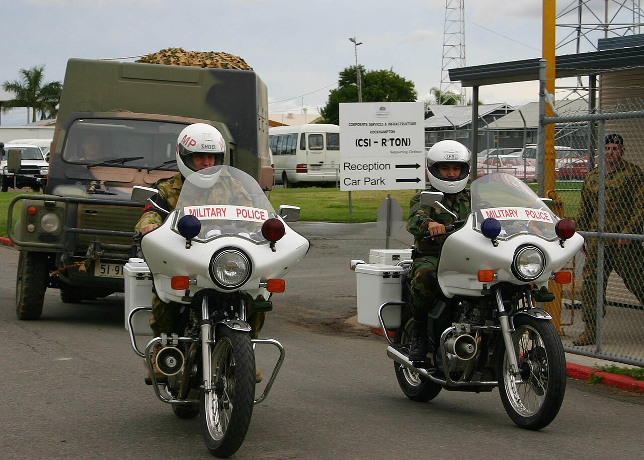 SRV(SF) — Canvas-topped Australian Army Perentie 110 4x4 (ARN 51-9xx, the RFSV/4x4 fleet number series) behind military police motorcycles at Camp Rocky, Queensland, during Talisman Sabre 2005