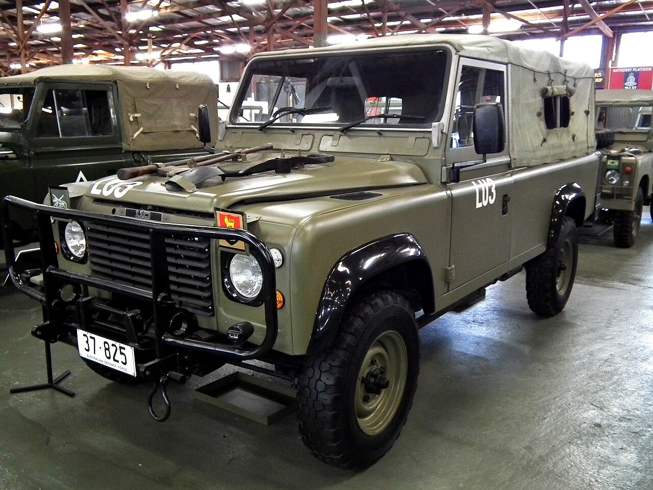 The subject exactly: a General Service Perentie 110 (ARN 37-825) at the Army Museum Bandiana in lustreless olive drab, hoops and tilt up, drop sides and full tailgate visible
