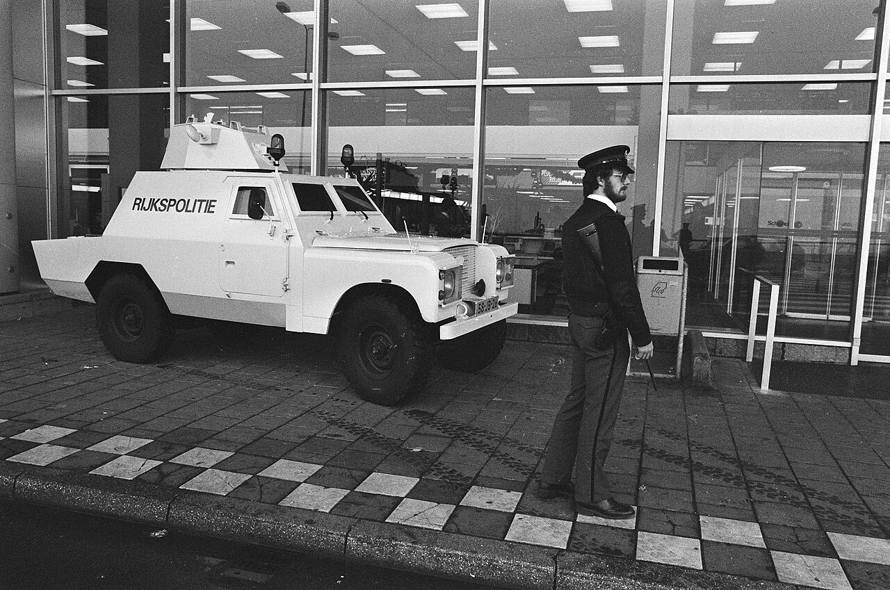Officer beside a Rijkspolitie Shorland during heightened security at Schiphol, 7 January 1986